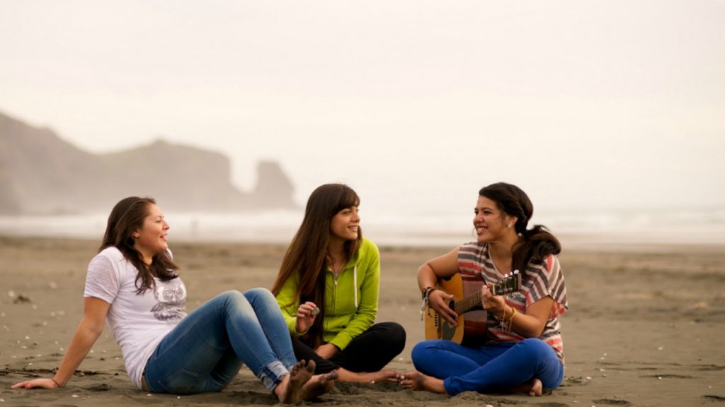 des amies sur la plage jouant de la guitare