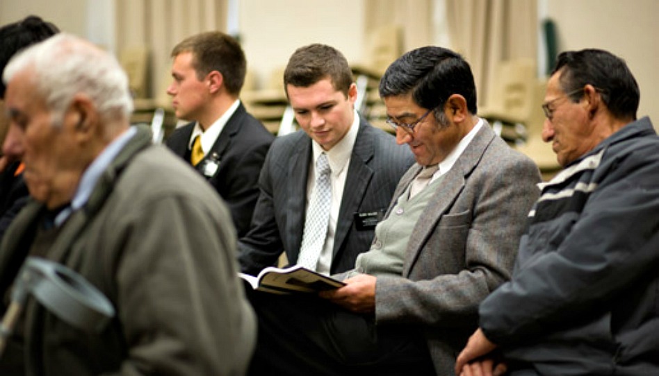 deux missionnaires et deux hommes lors d'une leçon de prêtrise